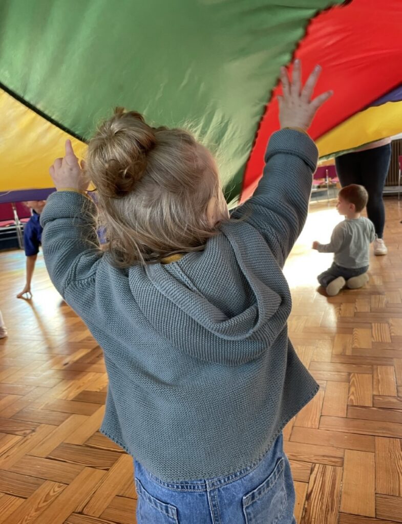 Child under parachute at Molly Moocow class